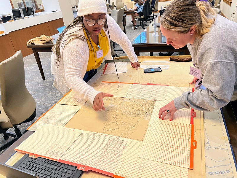 two women view a large map on a table