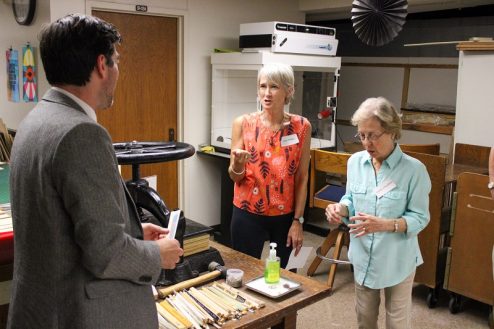 Zach Thompkins, LSU’s university archivist, shows off the spines removed from old books being restored to two tour participants in the conservation area of Hill Memorial Library.