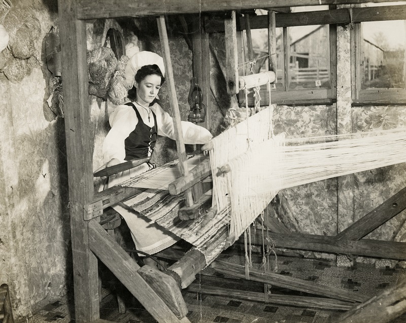 black and white image of a woman weaving on a large loom