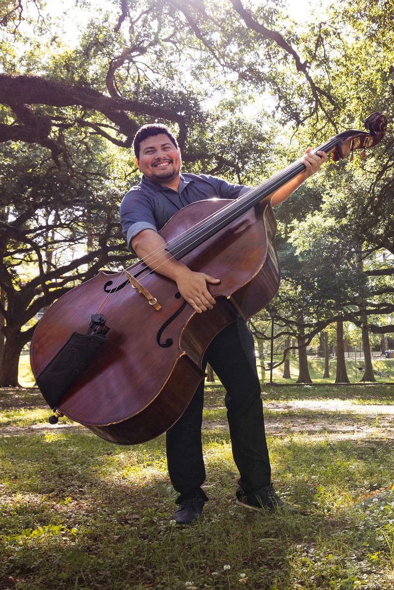 Moises smiling and holding a cello outside