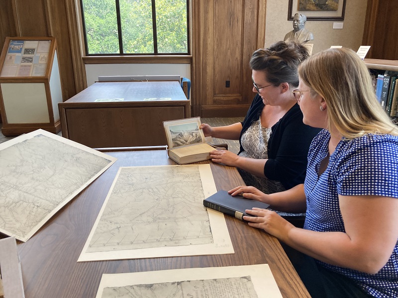 Two women look over a historic document in a library