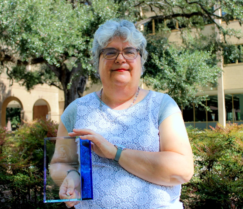 A woman holding an award outdoors