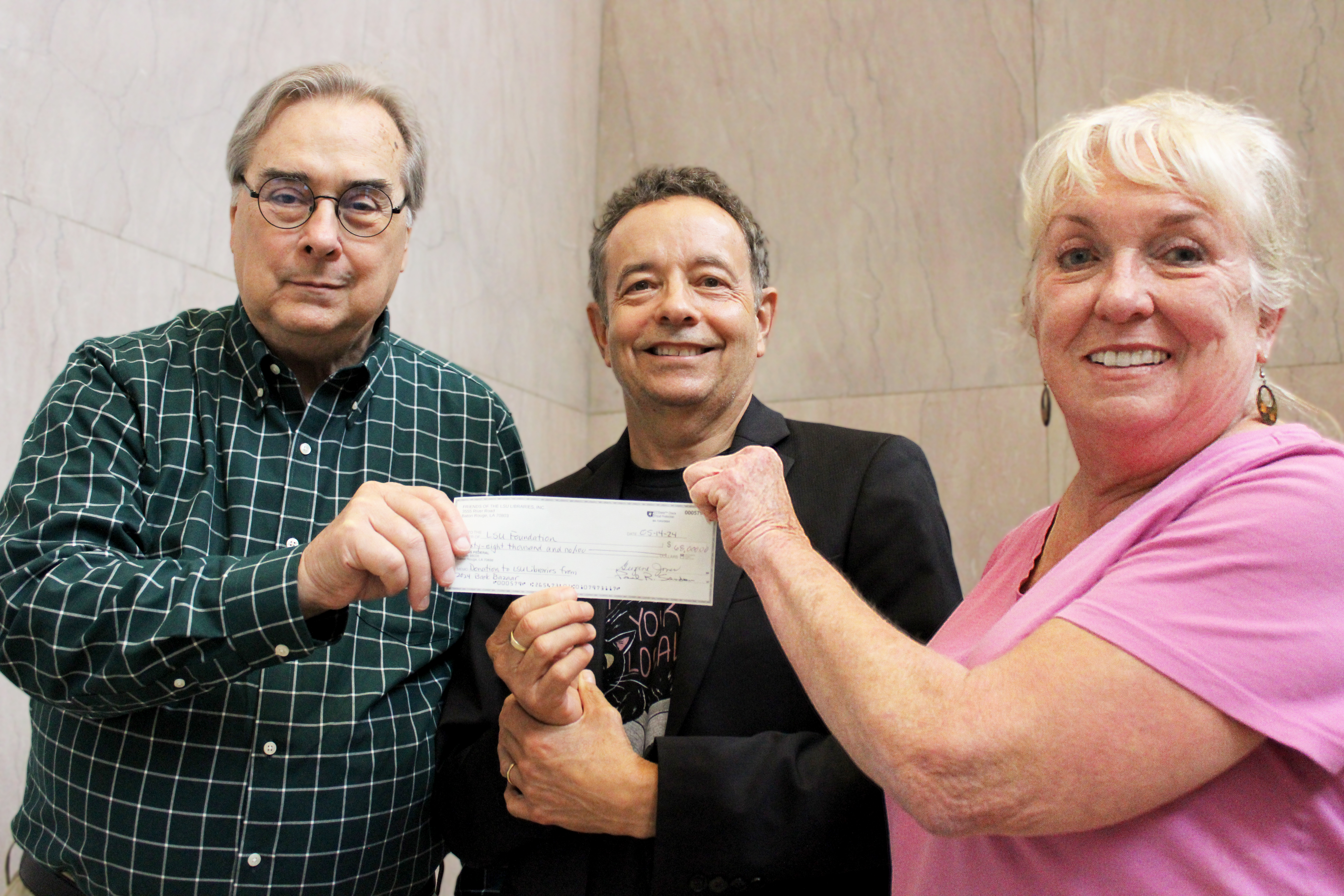 Three people pose with a check