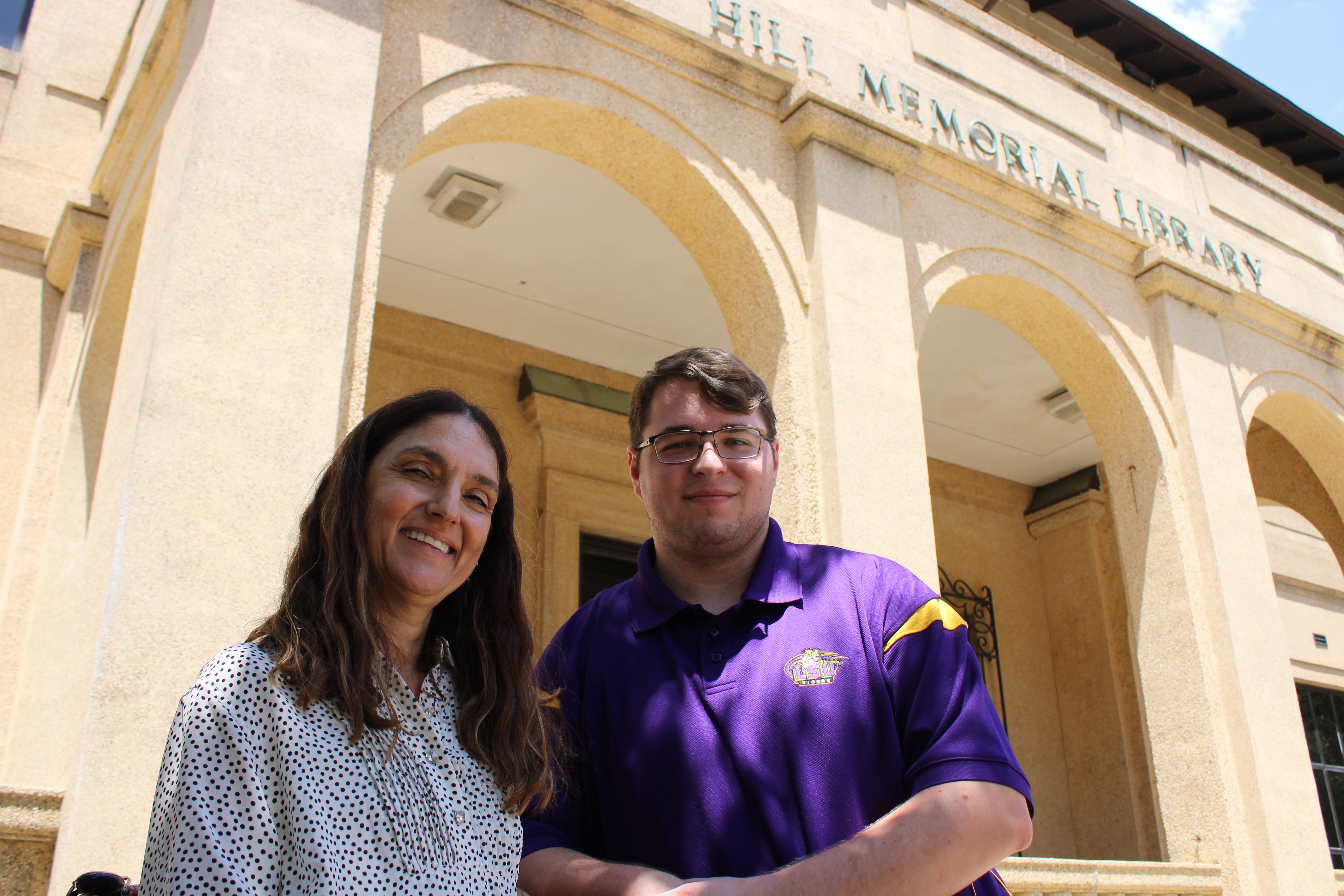 two people smile outdoors in front of Hill Memorial Library